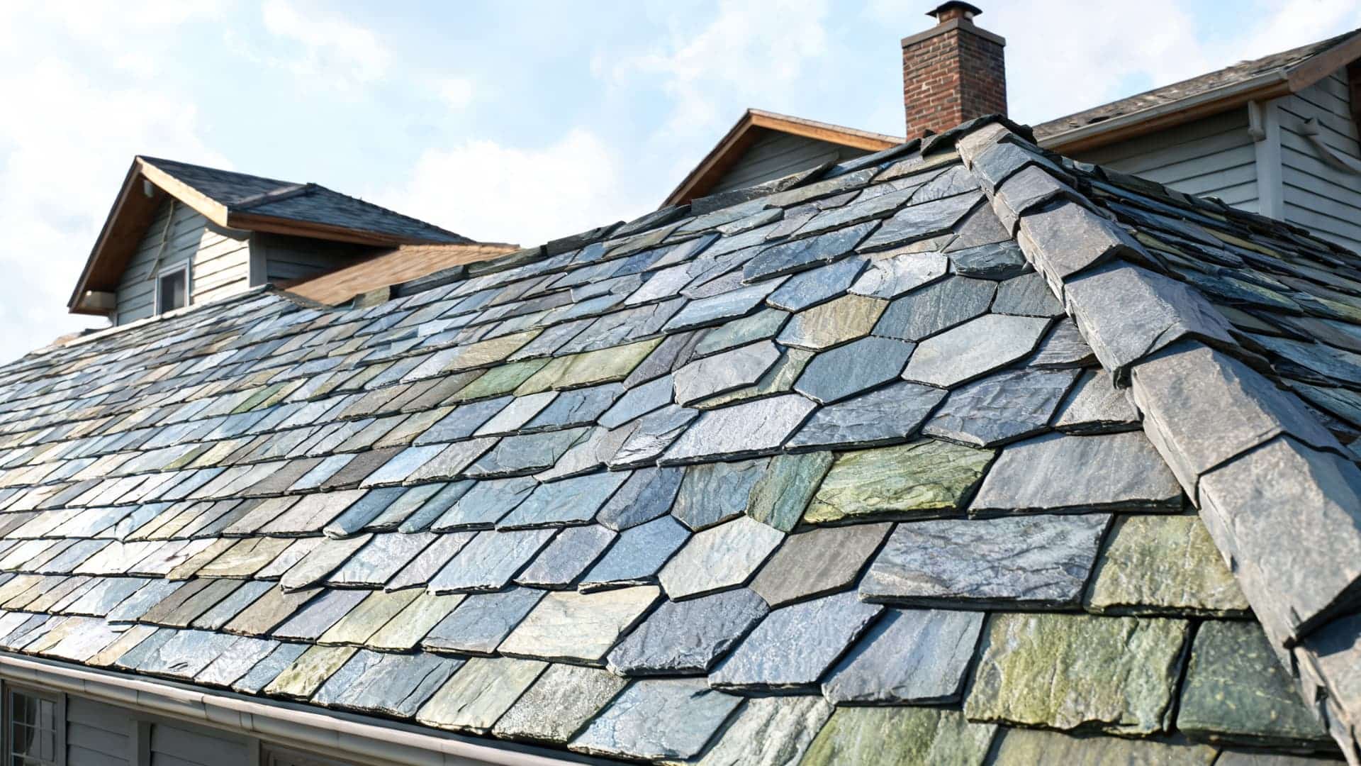 Newly fitted slate tiled pitched roof under a clear sky